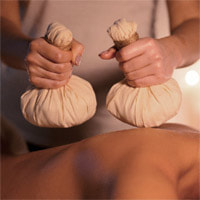 Client receiving Ayurvedic Pinda Sweda treatment of hot herbal poultices at Starling Holistic