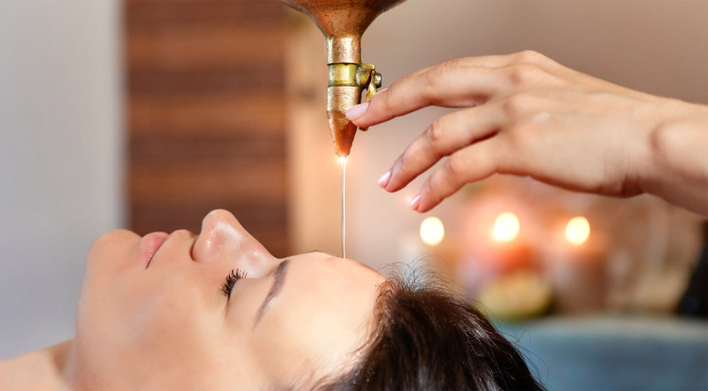 Client receiving a Shirodhara treatment of warm oil on the forehead at Starling Holistic in Arborfield near Reading